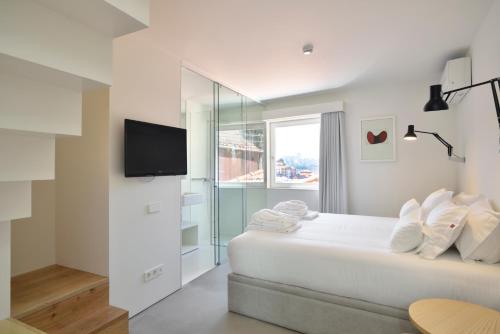 a white bedroom with a bed and a tv at House of Artists in Porto