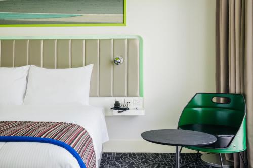 a hotel room with a bed and a green chair at Park Inn by Radisson Dubai Motor City in Dubai