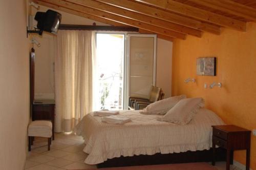 ein Schlafzimmer mit einem Bett und einem großen Fenster in der Unterkunft DIMITRA G TOLO APARTMENTs in Tolo