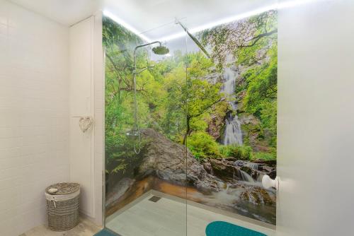 a bathroom with a shower with a waterfall mural at The Lidosol - Phenomenal view over the Atlantic Ocean in Funchal