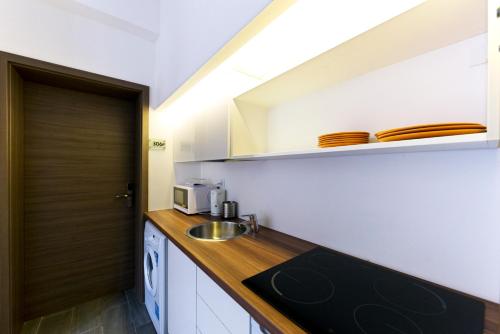 cocina con armarios blancos, fregadero y puerta en House Octogon, en Budapest