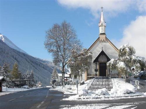 a church with a steeple on a snow covered street at Haus Birgit in Pettneu am Arlberg