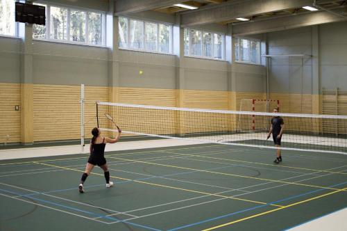 two people playing tennis on a tennis court at Hotel Srní a Depandance in Srní