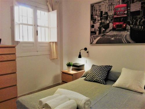 a bedroom with a bed with a window and a bus picture at Duplex En Corral De Vecinos San Bernardo in Seville