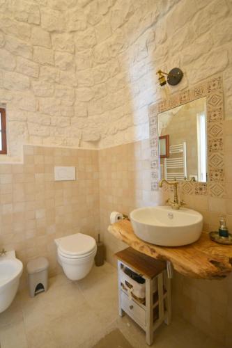 a bathroom with a sink and a toilet and a mirror at Trulli Petra Chiara in Locorotondo