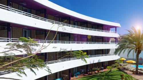 a building with a pool and palm trees at Jacarandas Beach in Playa del Ingles