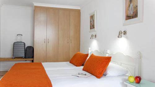 a bedroom with a white bed with orange pillows at Jacarandas Beach in Playa del Ingles