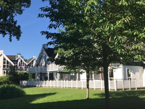 a house with a white fence and a tree at Ferienpark Bad Saarow in Bad Saarow