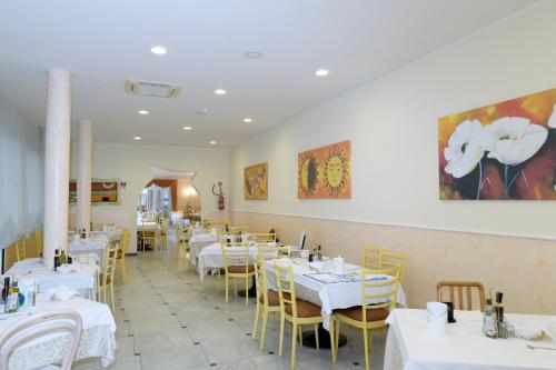 une salle à manger avec des tables blanches et des chaises jaunes dans l'établissement Mondial, à Cervia