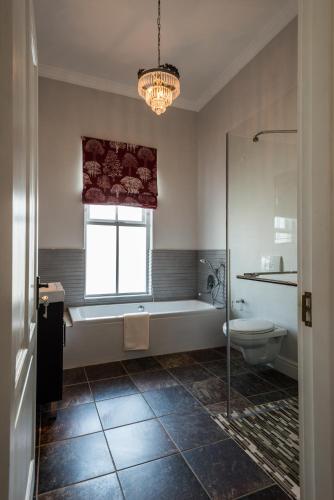 a bathroom with a tub and a toilet and a window at Waterstone Lodge in Somerset West