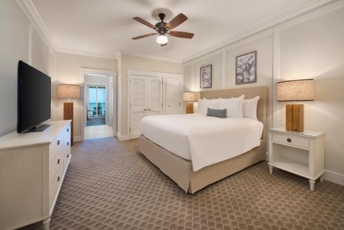 a bedroom with a white bed and a flat screen tv at Jekyll Ocean Club Resort in Jekyll Island
