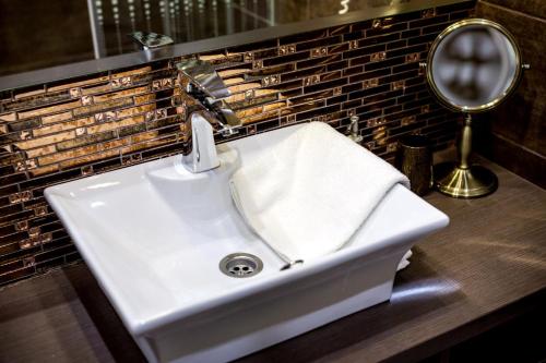 a white sink in a bathroom with a mirror at Royal Apartments Hotel Kecskemét in Kecskemét