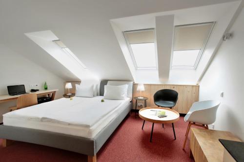 Absolutum Wellness Hotel في براغ: غرفة نوم بسرير وكرسيين وطاولة