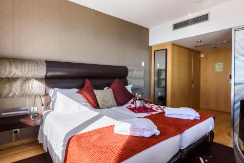 um quarto com uma cama grande e toalhas em Luna Hotel dos Carqueijais - Serra da Estrela na Covilh
