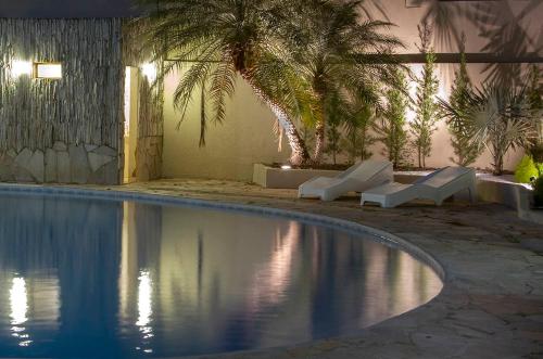 a swimming pool with white loungers and a palm tree at Hotel Morada das Águas in Caldas Novas