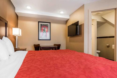 a hotel room with a large bed with a red bedspread at Rodeway Inn Chicago/Evanston in Lincolnwood