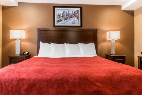 a bedroom with a red bed with two lamps at Rodeway Inn Chicago/Evanston in Lincolnwood