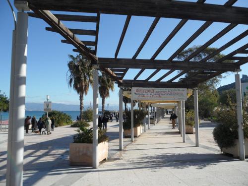 a wooden pergola on a sidewalk next to the beach at Fede & Francy in Quartu SantʼElena