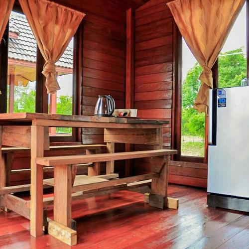 a wooden cabin with a table and a refrigerator at Home Style Resort in Buriram