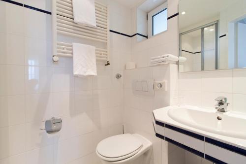 a white bathroom with a toilet and a sink at Hotel Seeblick Garni in Plön