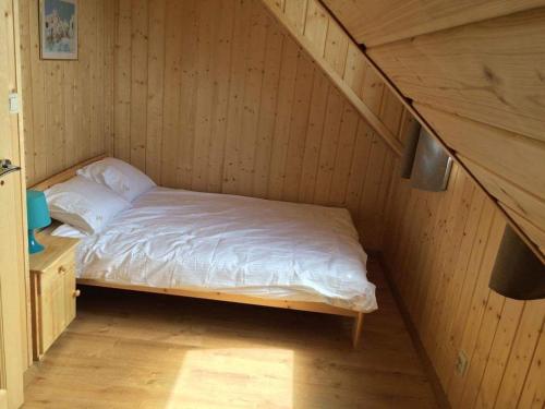 a bed in a room with a wooden wall at Domki letniskowe La Familia in Sianozety