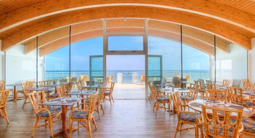 restauracja ze stołami i krzesłami oraz widokiem na ocean w obiekcie Regent's Hotel w mieście Lido di Jesolo