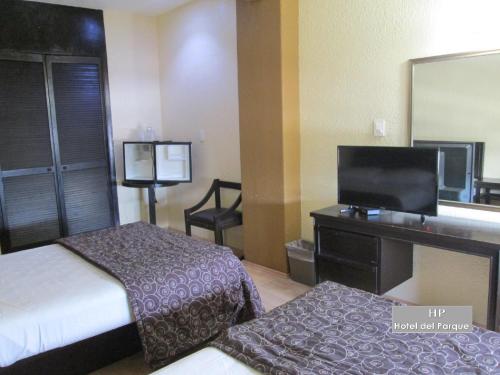 a hotel room with two beds and a flat screen tv at Hotel Del Parque in Guadalajara
