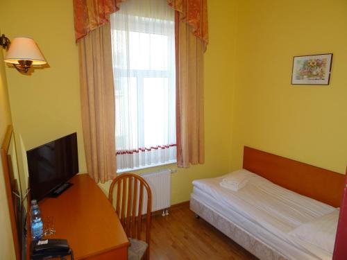 a bedroom with a bed and a desk and a window at Hotel Bartis in Bartoszyce
