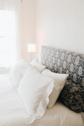 a bed with white pillows and a gray headboard at Chebeague Island Inn in Royal Junction