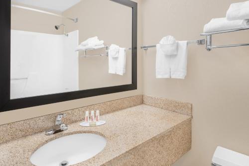 a bathroom with a sink and a mirror and towels at Super 8 by Wyndham Marshalltown in Marshalltown
