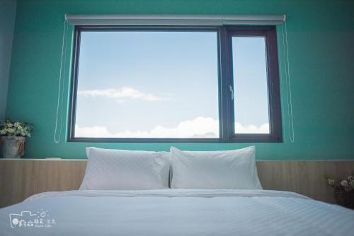 a bed with white pillows in front of a window at Simple Life in Yuli