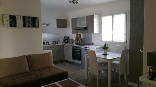 a living room with a couch and a table in a kitchen at Cottage sword beach in Hermanville-sur-Mer