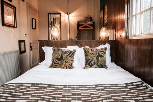 una camera da letto con letto, lenzuola e cuscini bianchi di The Pilot Inn a Londra