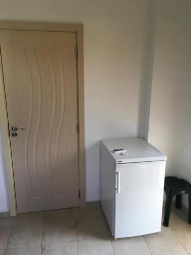 a white refrigerator and a door in a room at Zapovedni Rai in Primorsko