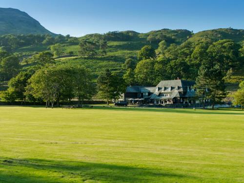 a large grass field with a house in the distance at Glaramara Hotel in Borrowdale