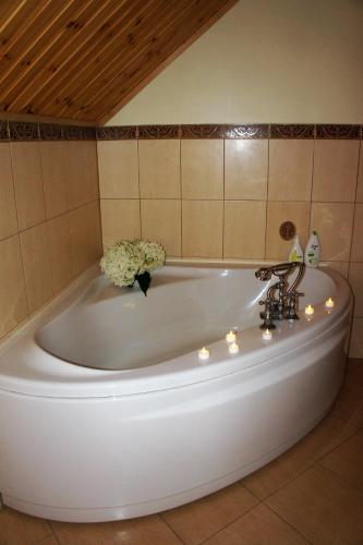 a bath tub with a vase of flowers and lights at Dom Wilków in Leoncin