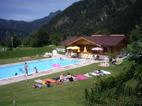 eine Gruppe von Menschen, die im Gras an einem Pool liegen in der Unterkunft Gut Hanneshof in Erpfendorf