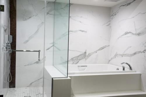 a white bathroom with a shower and a tub at Hotel Xilo Glendale in Glendale