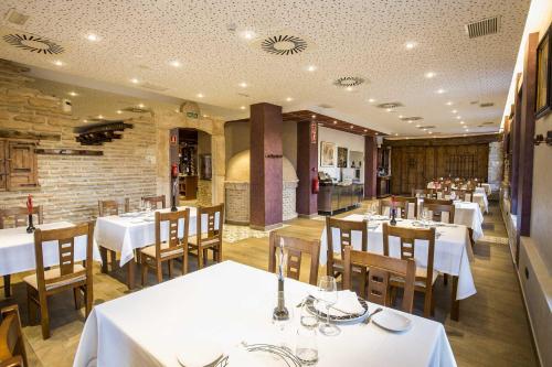 a restaurant with white tables and chairs in a room at Hotel SPA El Lagar de Isilla in La Vid y Barrios