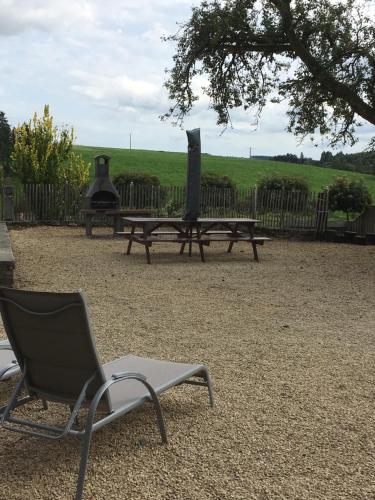 a chair sitting next to a picnic table and a grill at Le gîte de la vieille église in Tenneville