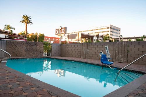 a swimming pool with a blue chair and a building at Hotel Xilo Glendale in Glendale