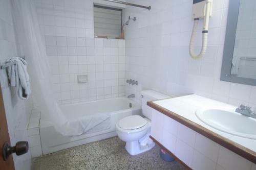 a white bathroom with a toilet and a sink at Sahara Hostel in Montego Bay