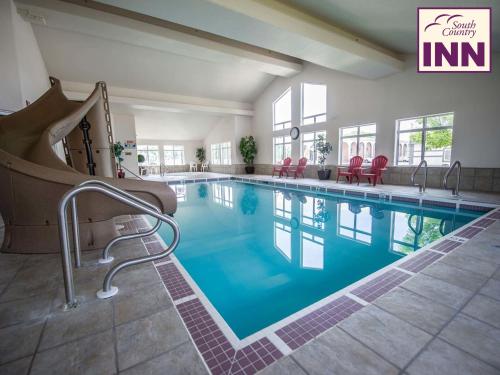 une piscine dans un hôtel avec des chaises et des tables rouges dans l'établissement South Country Inn, à Cardston