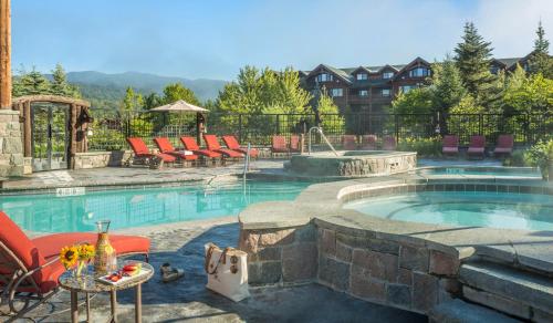 a swimming pool with chairs and a table next to it at The Whiteface Lodge in Lake Placid