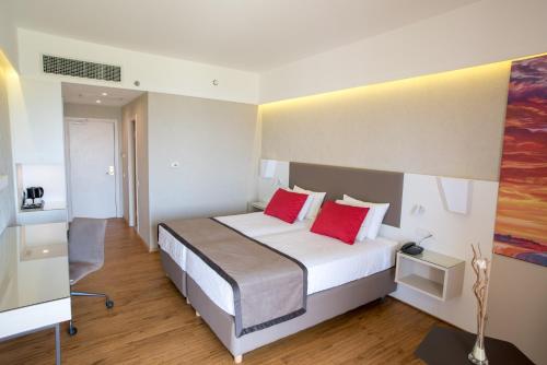 a hotel room with a bed with two red pillows at Ramada Plaza by Wyndham Thraki in Alexandroupoli