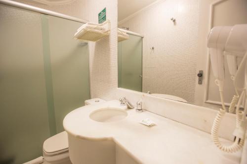 a bathroom with a sink and a toilet and a mirror at Hotel Ipanema de Sorocaba in Sorocaba