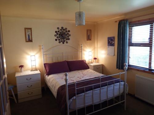 a bedroom with a bed with two night stands and two windows at 16 Mounthooly Street in Lerwick