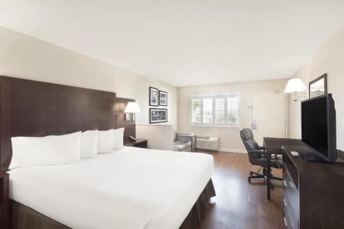 Habitación de hotel con cama blanca grande y escritorio. en Baymont by Wyndham Modesto Salida en Modesto
