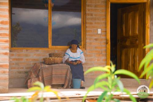 a woman sitting on the porch of a building at Casa Hotel Loma Wasi en Cotacachi in Cotacachi