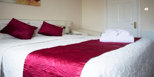 Una cama blanca con almohadas rojas y toallas. en Balcony House, en Galway